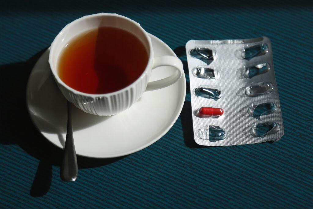 A photo of a cup of tea with a blister pack of iron pills next to it.