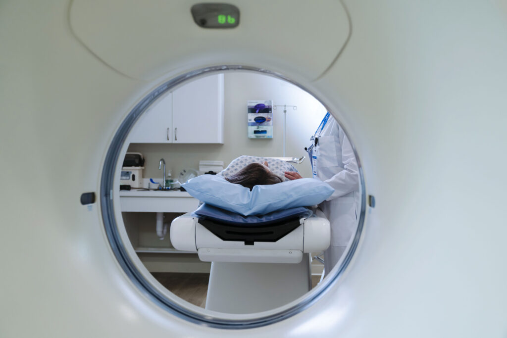 A doctor stands beside a patient about to go through a CT scanner, just out of view.