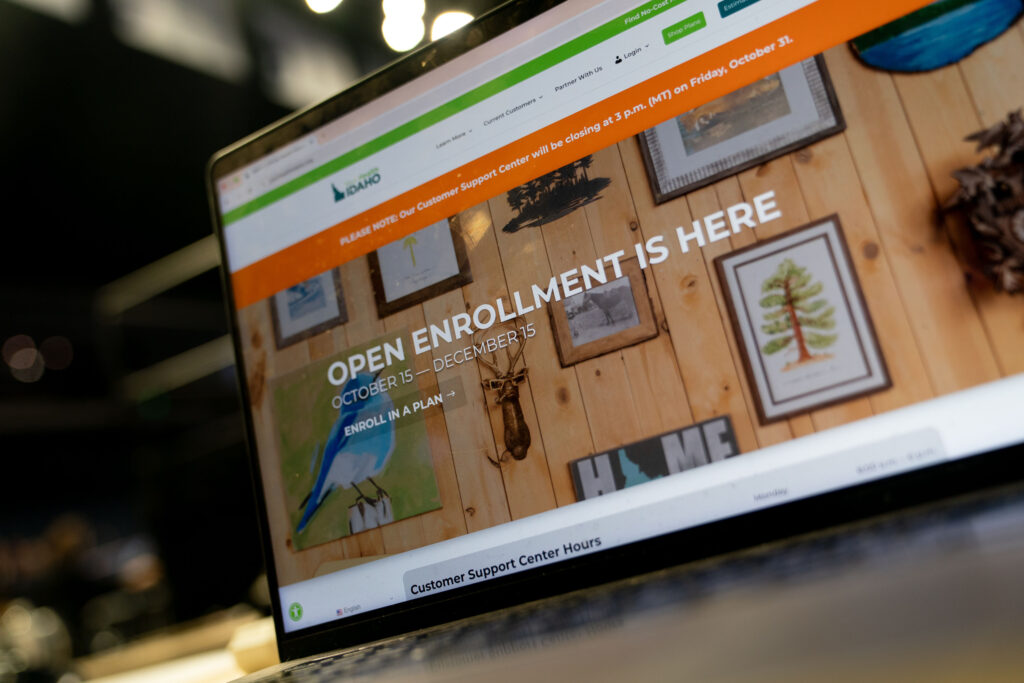 A laptop screen shows Idaho's Affordable Care Act marketplace website, with "Open Enrollment Ends December 15" in all-cap tyoe.