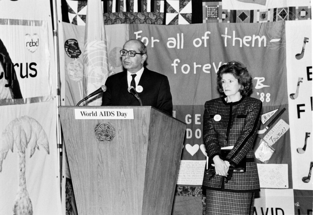A black and white photograph from 1988 shows Rafeeuddin Ahmed, Chairman of the UN Steering Committee for the Prevention and Control of AIDS, speaking at the opening ceremony. On the right is Mrs. M Perez de Cuellar, wife of the UN Secretary-General.